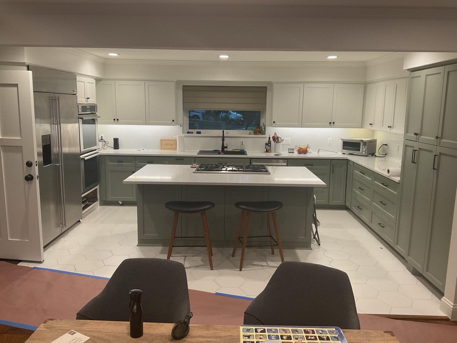 The same kitchen finished: sage green cabinets, cream uppers, white quartz counters and hex tile floor
